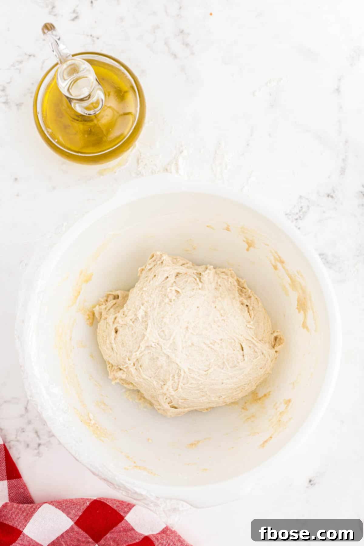 Perfect Sourdough Pizza Dough 11 Sourdough pizza dough resting in a white bowl after several rounds of stretching and folding, appearing smoother and more elastic.