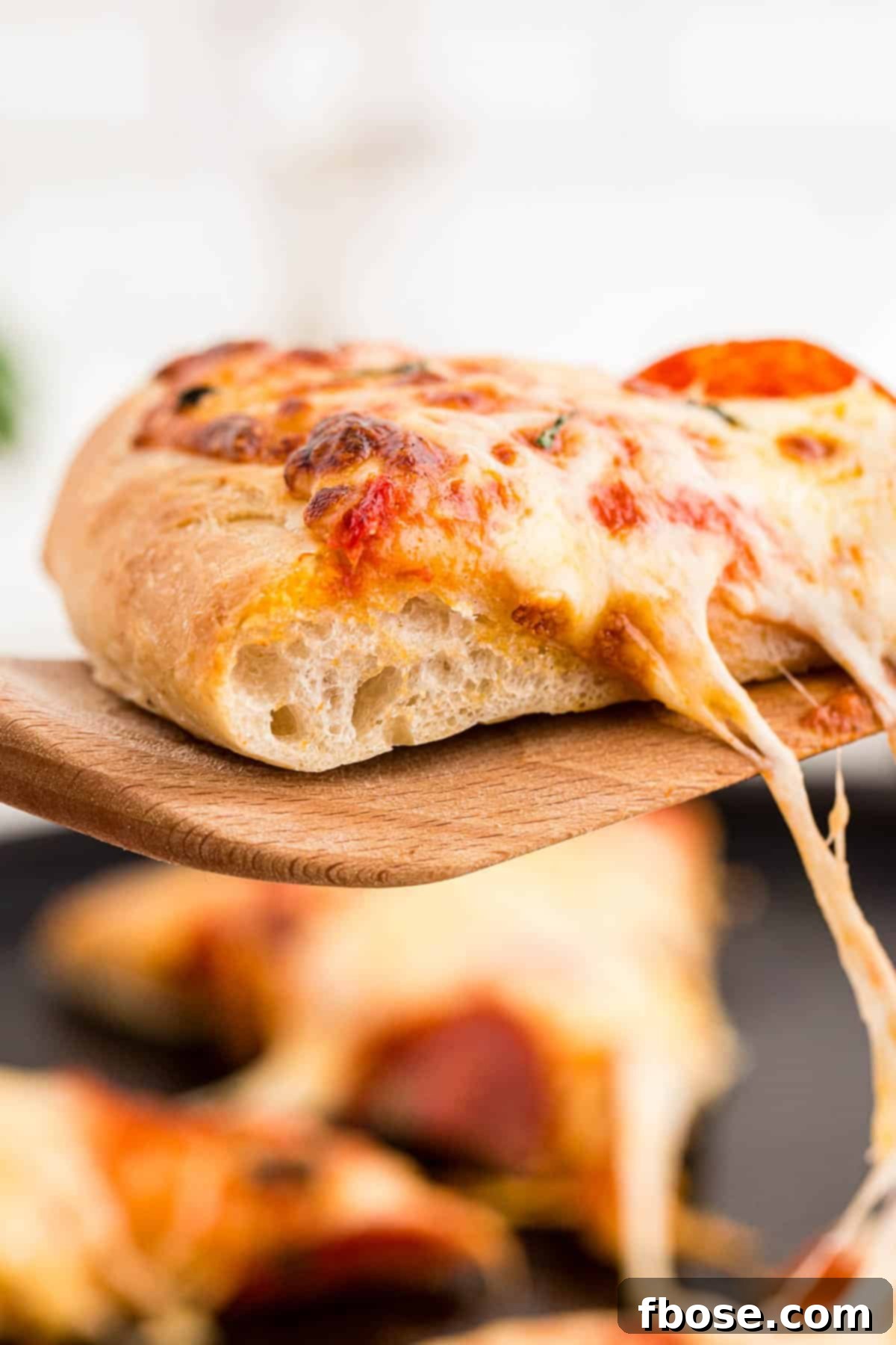 Perfect Sourdough Pizza Dough 18 A freshly baked slice of sourdough pizza being pulled from the main pizza, demonstrating the delicious, stretchy cheese and perfect crust.