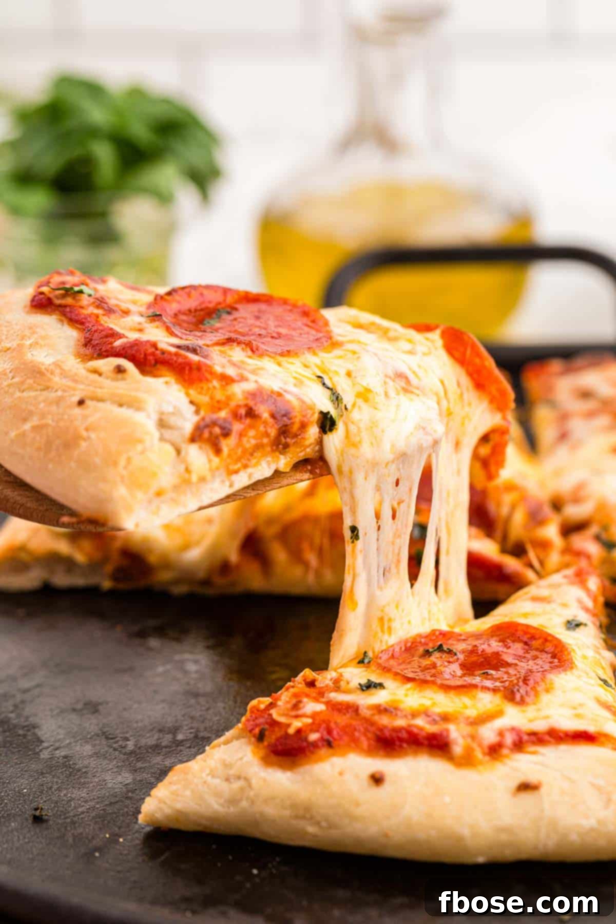 Perfect Sourdough Pizza Dough 3 A delectable slice of sourdough pizza being lifted from the pan, showcasing its irresistible cheesy pull and perfectly baked crust.