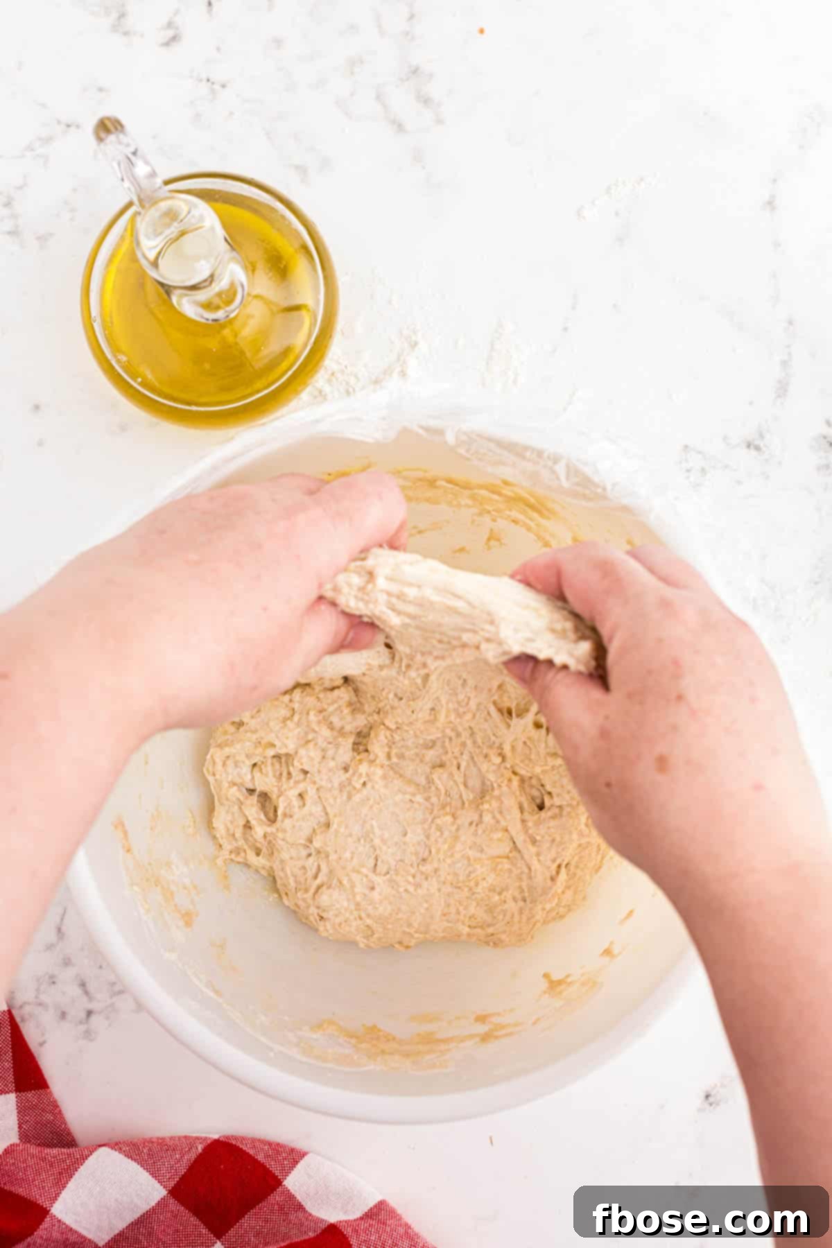 Perfect Sourdough Pizza Dough 9 Sourdough pizza dough being actively stretched and folded within a bowl, illustrating the technique to build dough strength.