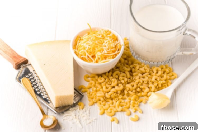 Assortment of fresh ingredients laid out neatly on a white wooden table, including pasta, cheese, and milk, ready for making mac and cheese in a mug.