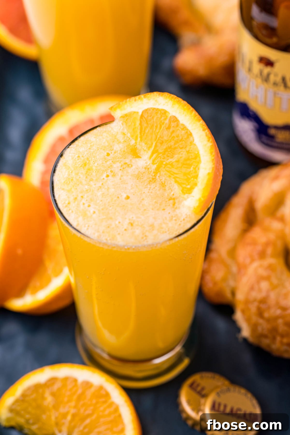 Close up photo of a beermosa surrounded by orange slices and croissants, highlighting its refreshing appeal.