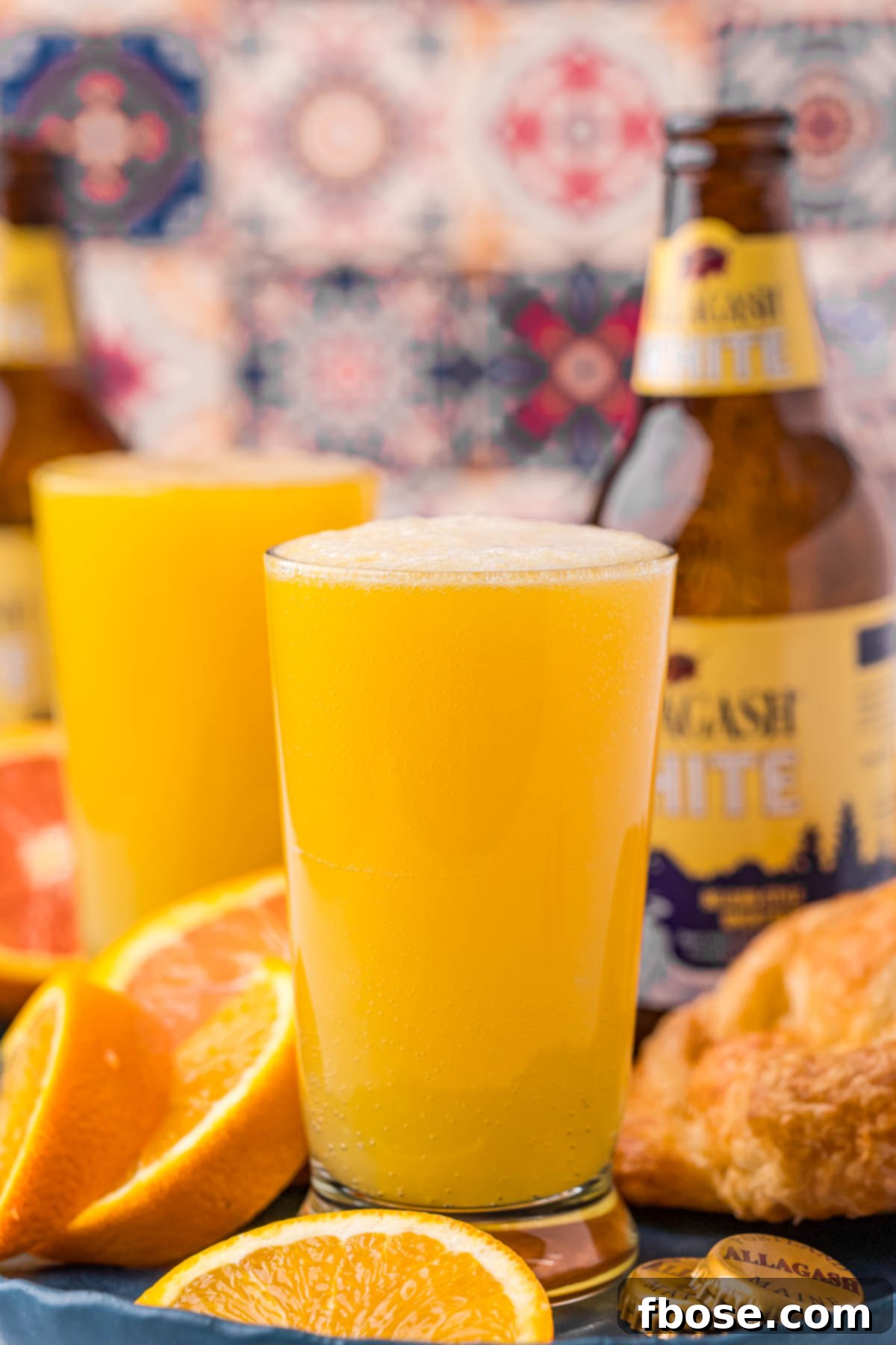 Straight on photo of a beermosa with a bottle of Allagash White in the background, showing the ingredients in context.