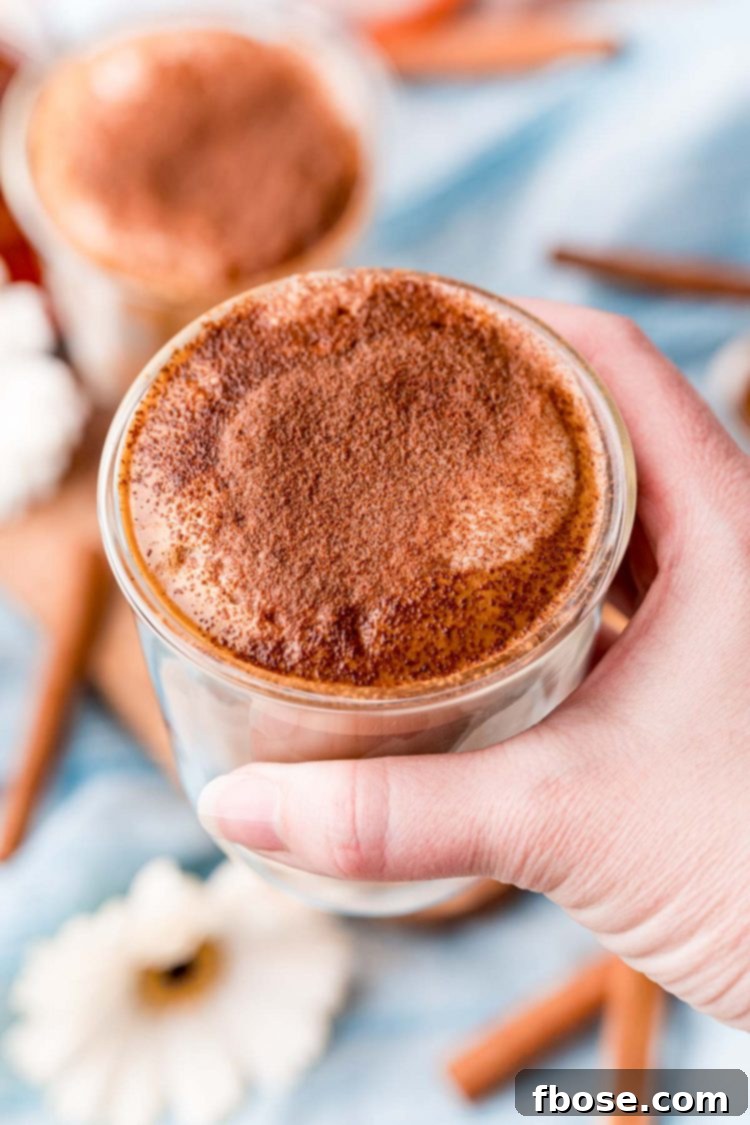 A woman's hand holding a glass with cafe con miel close to the camera.