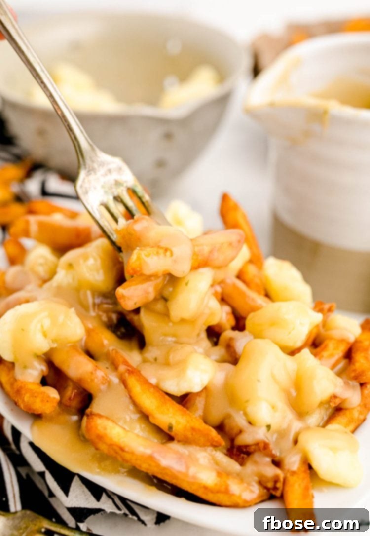 Close up photo of poutine with a fork taking a bite out of it.