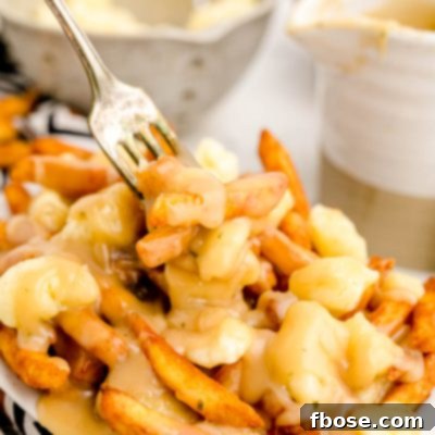 Close up photo of poutine with a fork taking a bite out of it.