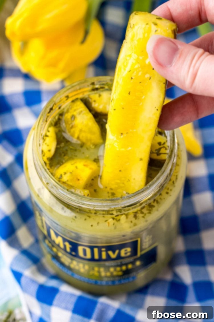 A woman's hand reaching into a jar to pull out a ranch-seasoned pickle spear.