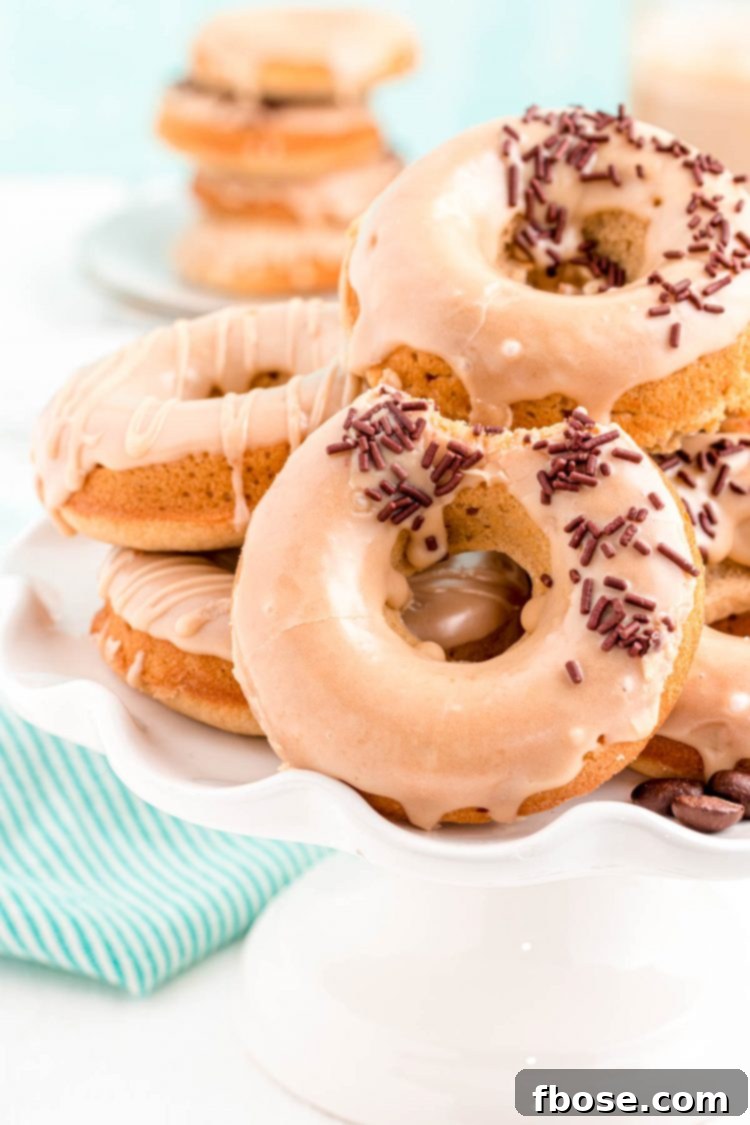 Brewed & Baked 6 Close up photo of coffee donuts arranged on a white cake stand with a teal napkin in the background, highlighting their elegant presentation.