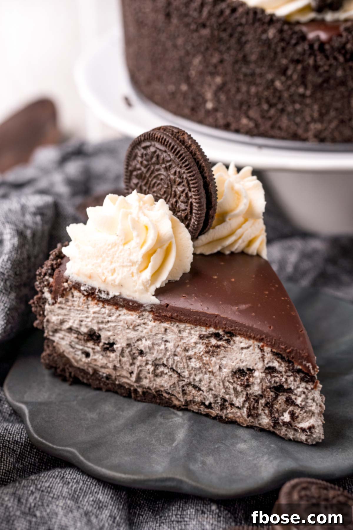 Oreo No-Bake Cheesecake Delight 3 Close-up side view of a slice of no-bake Oreo cheesecake on a gray plate, showcasing the distinct layers.