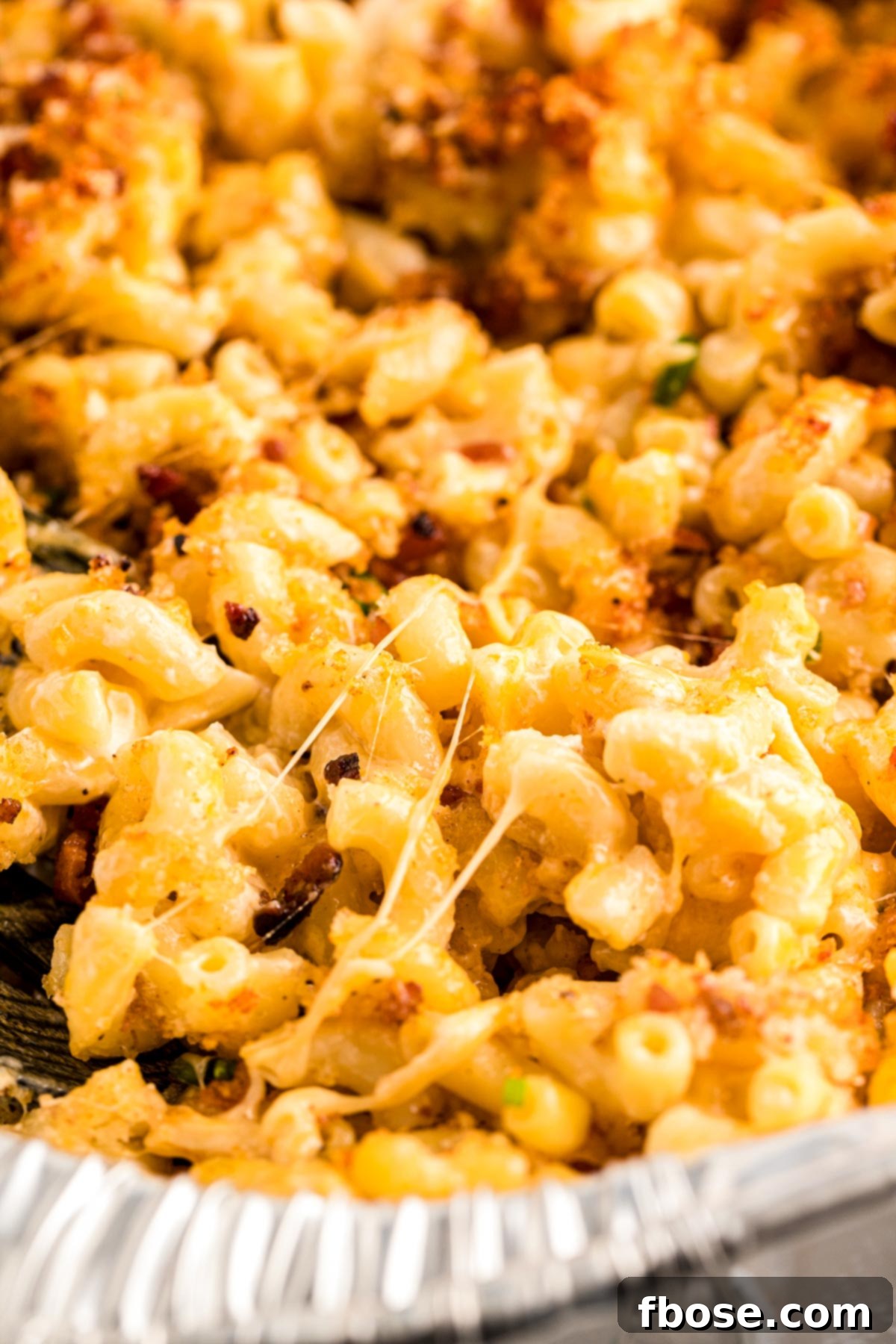 Close up photo of a pan of smoked mac and cheese, showing the golden-brown, crispy topping and bubbling cheese underneath.