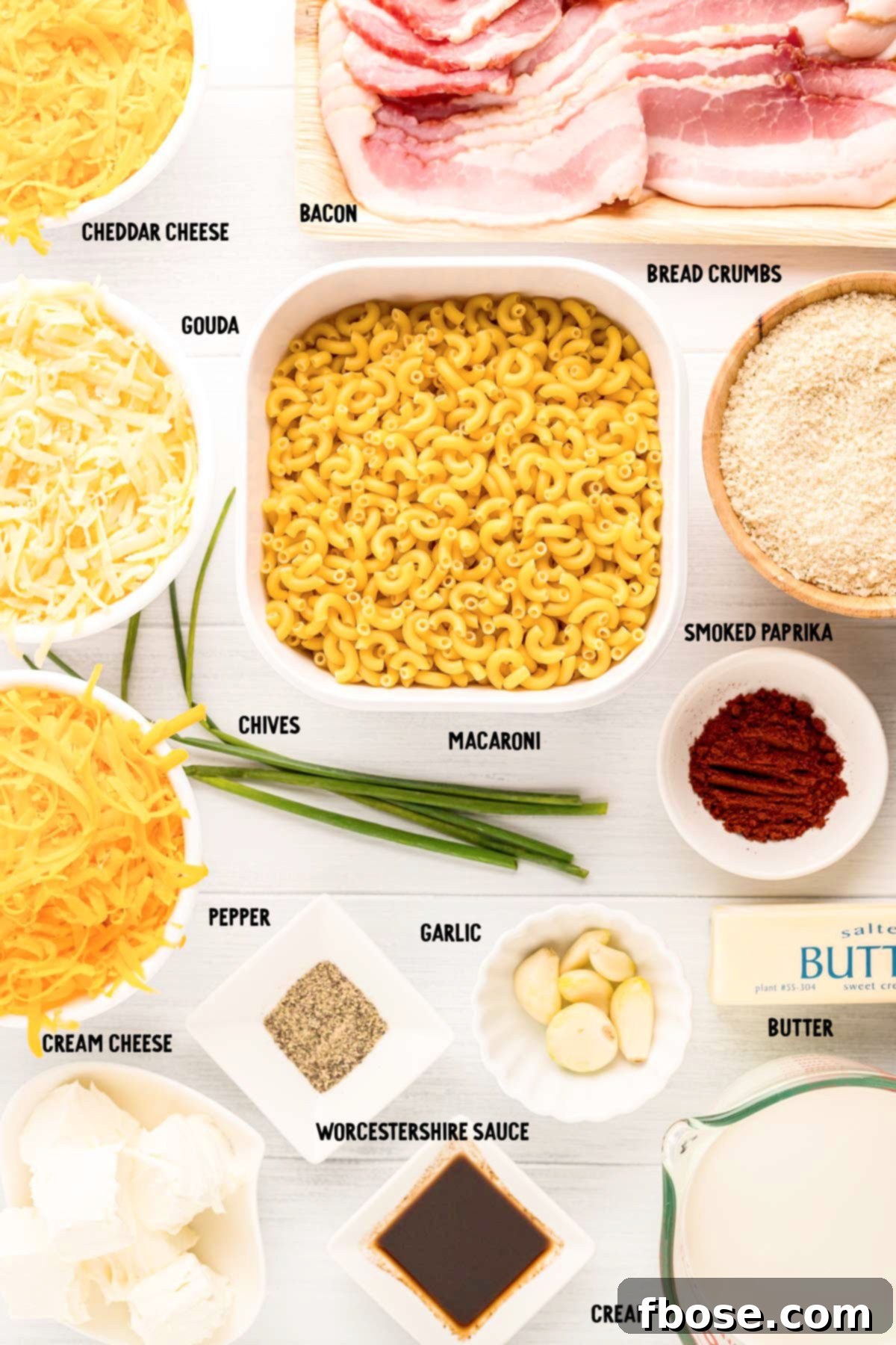 OVERHEAD PHOTO OF INGREDIENTS PREPPED ON A MARBLE COUNTER TO MAKE SMOKED MAC AND CHEESE, showcasing fresh cheeses, pasta, bacon, and seasonings.