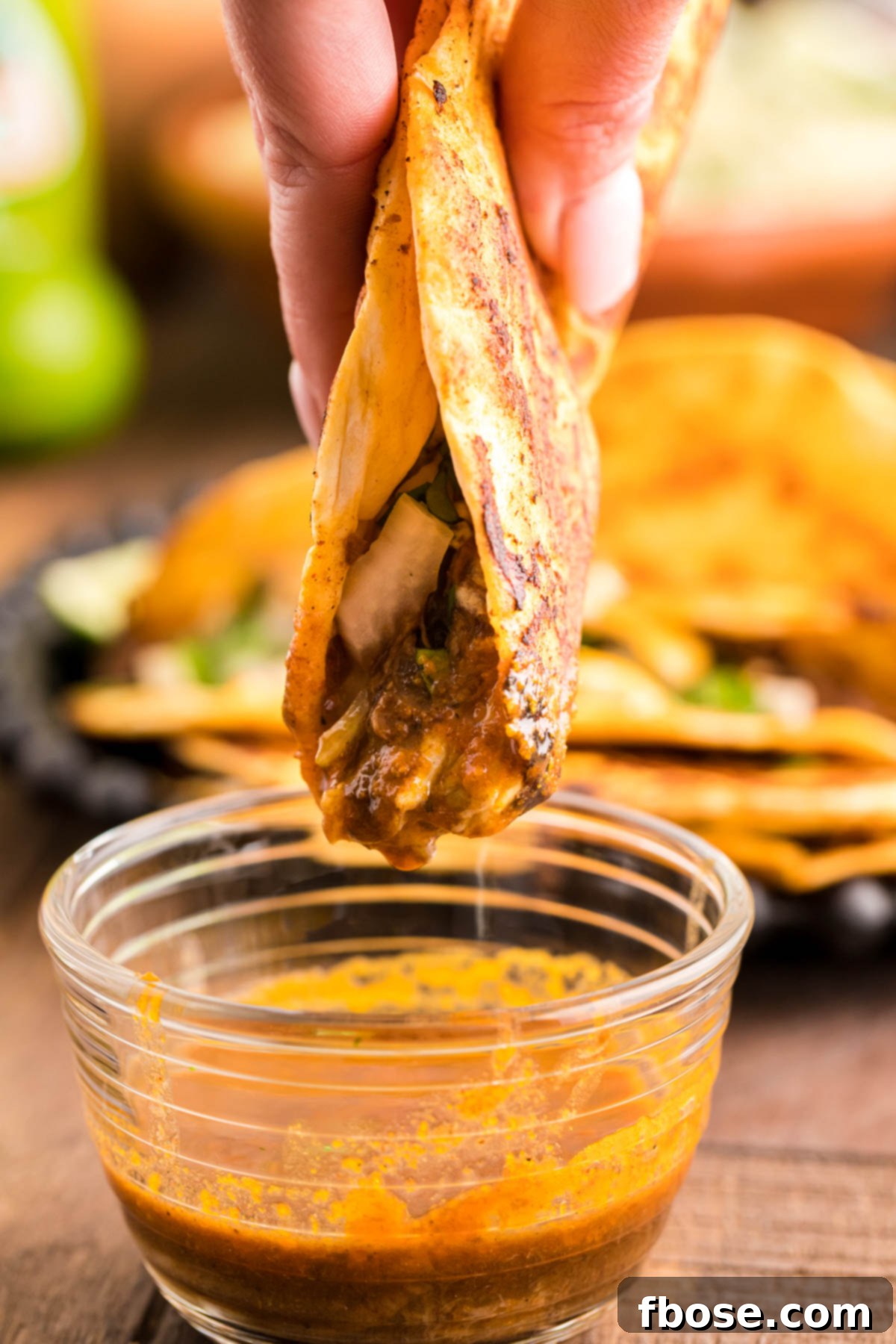 Birria taco being dipped in sauce.