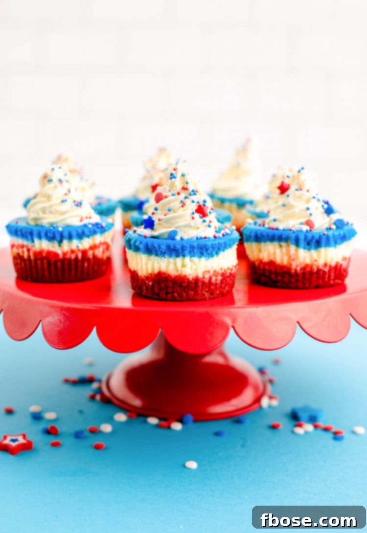 Red White & Blue Mini Cheesecakes 6 red, white, and blue mini cheesecakes for the 4th of july on a red cake stand on a blue surface.