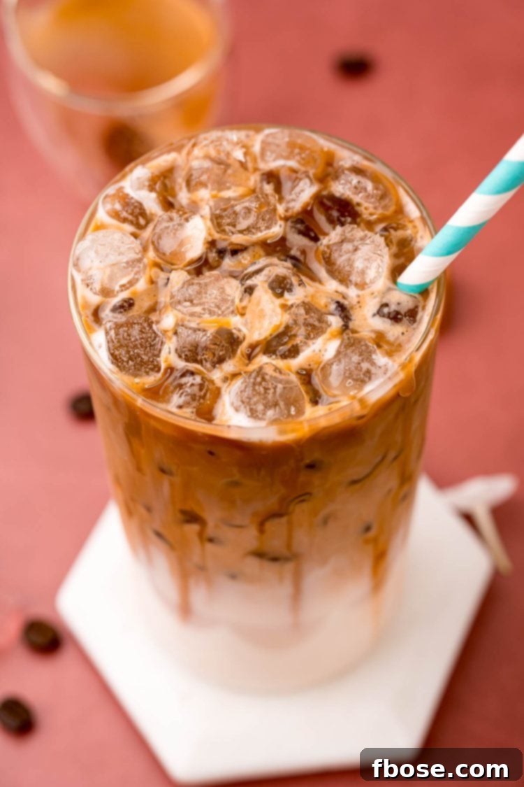 Close up photo of a glass filled with an iced caramel macchiato.