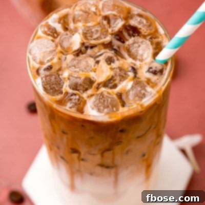 Close up photo of a glass filled with an iced caramel macchiato.