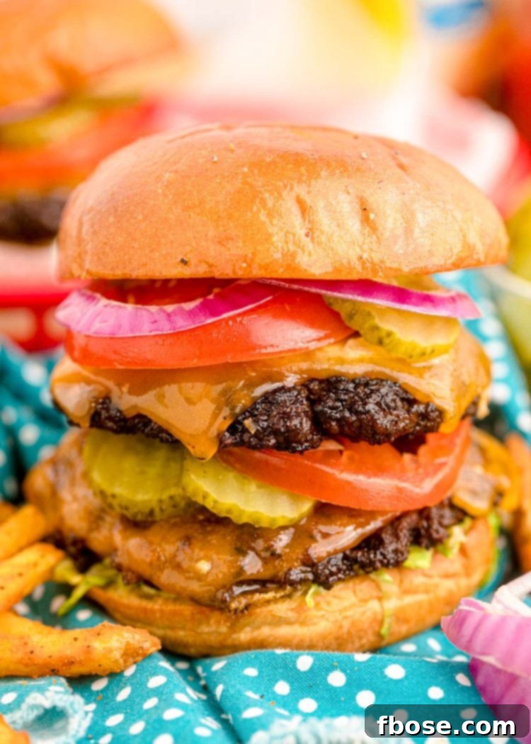 Close up of a smash burger topped with pickles, tomatoes, onions, and more.