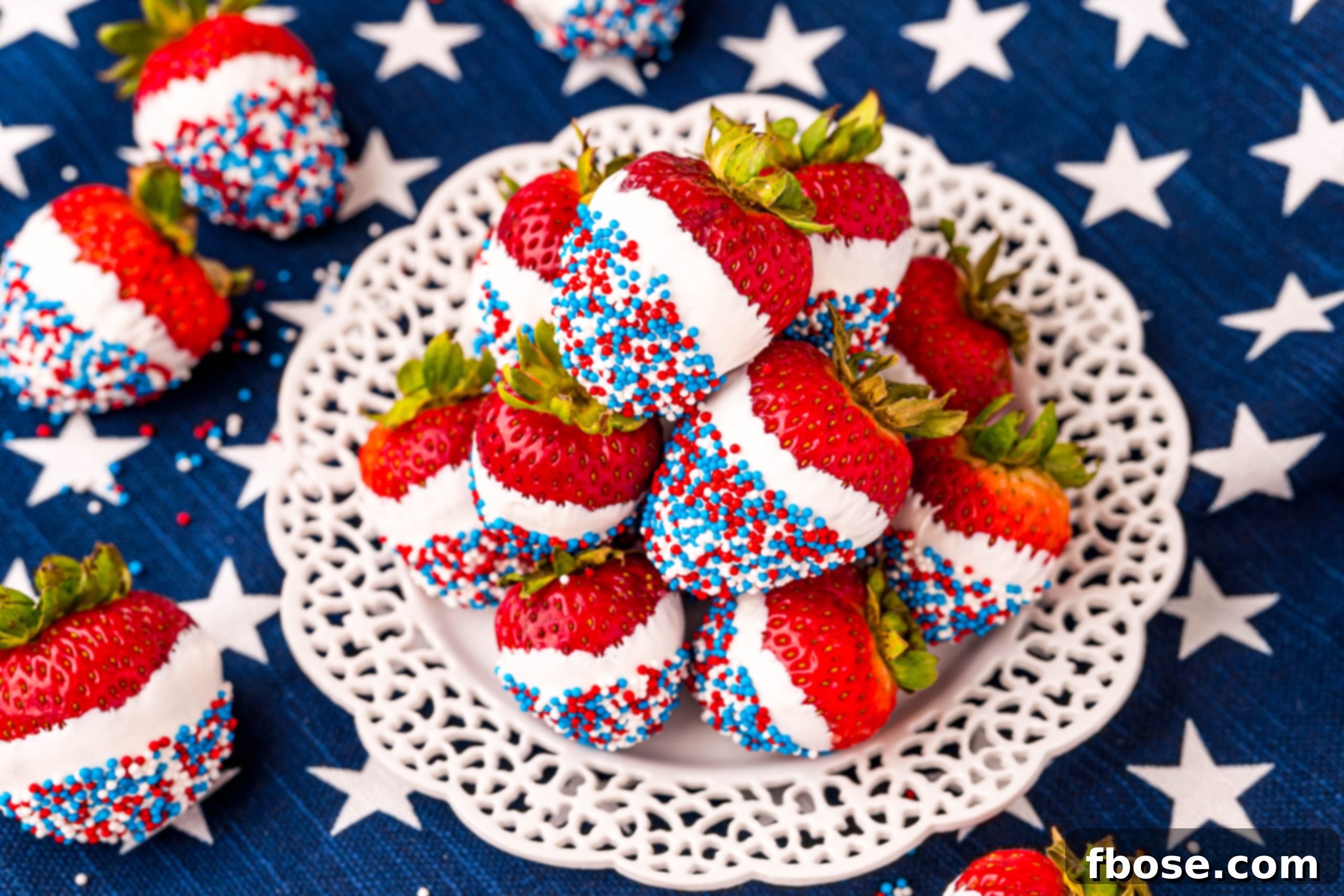 Independence Day Strawberry Delights 6 Red, white, and blue dipped strawberries on a white plate on a blue and white star printed napkin.