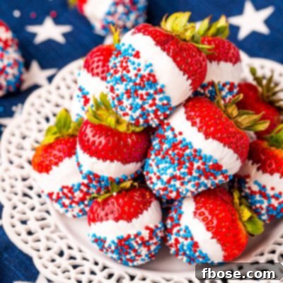 Independence Day Strawberry Delights 7 Close up photo of a while plate on a blue and what star napkin with strawberries that have been dipped in white candy then in red, white, and blue sprinkles.