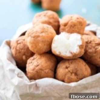 A close-up of finished Irish Potato Candy dusted with cinnamon, resembling small potatoes, on a white plate.