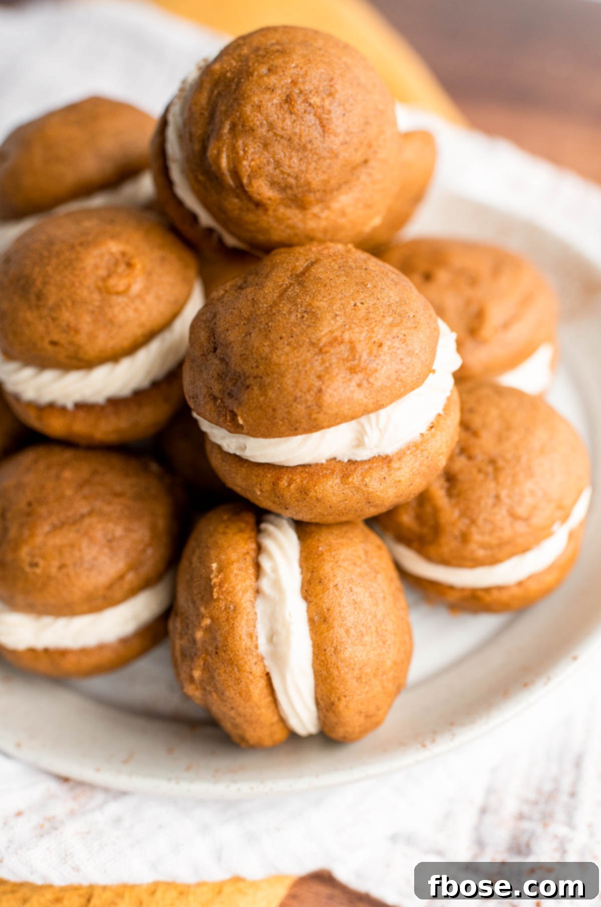 A white plate filled with mini pumpkin whoopie pies.