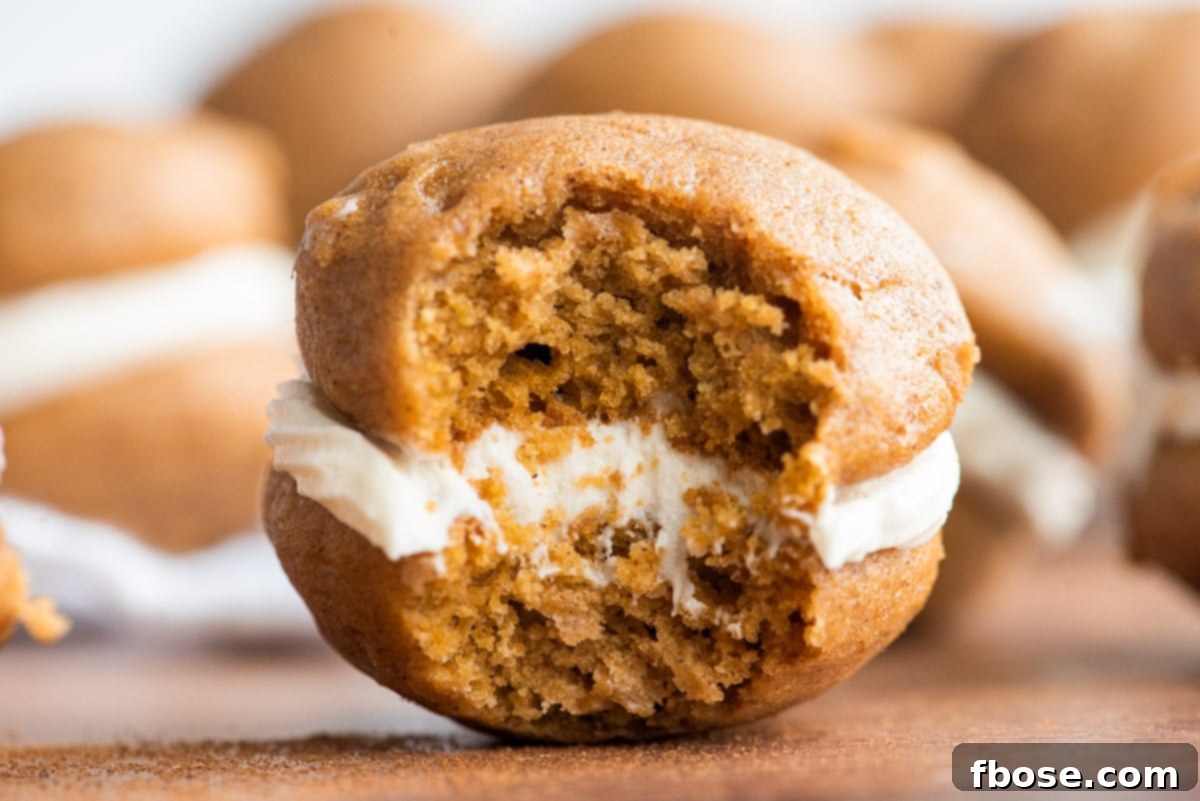 Close up photo of a pumpkin whoopie pie with a bite taken out if it.