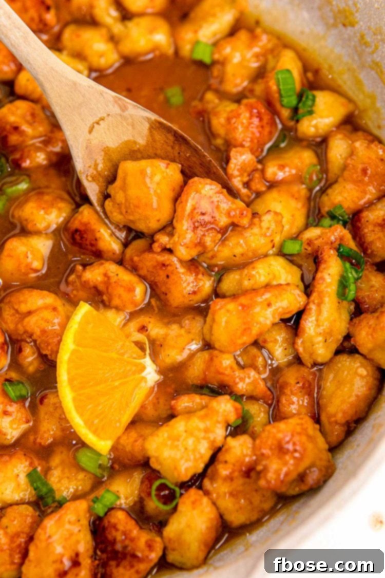 Close up photo of orange chicken being cooked in a skillet.