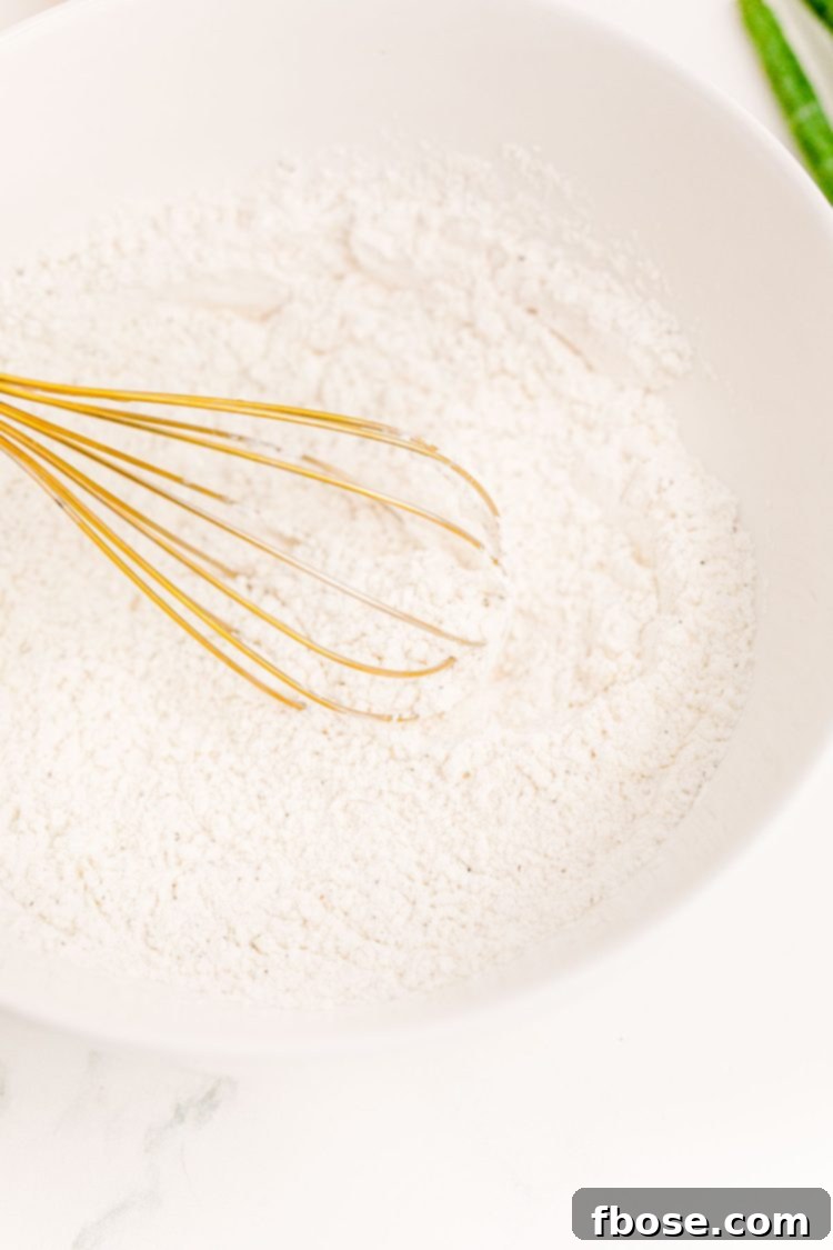 Flour and cornstarch being whisked together in a white mixing bowl.