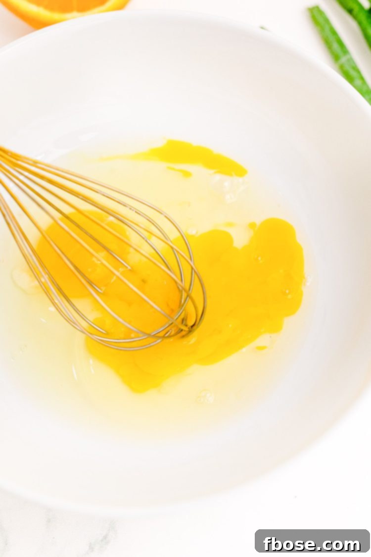 Eggs being beaten in a white bowl.