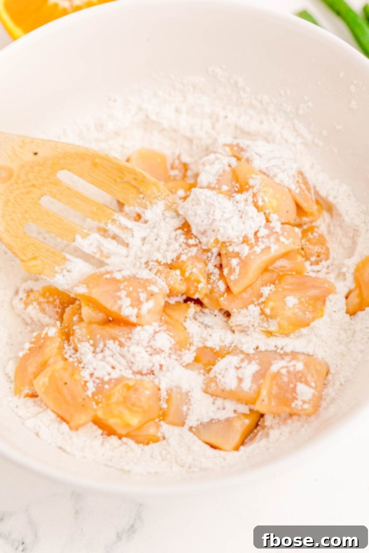 Chicken pieces being coated in flour.