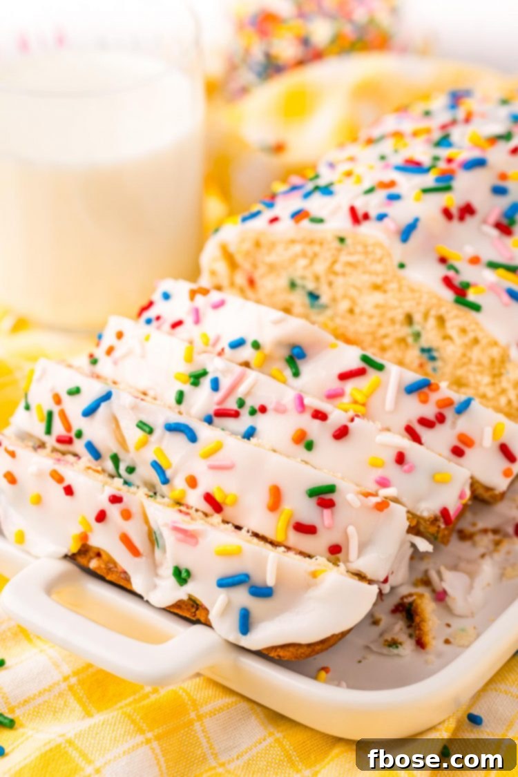 Close up photo of a white plate with a sliced funfetti bread on it with a glass of milk in the background.