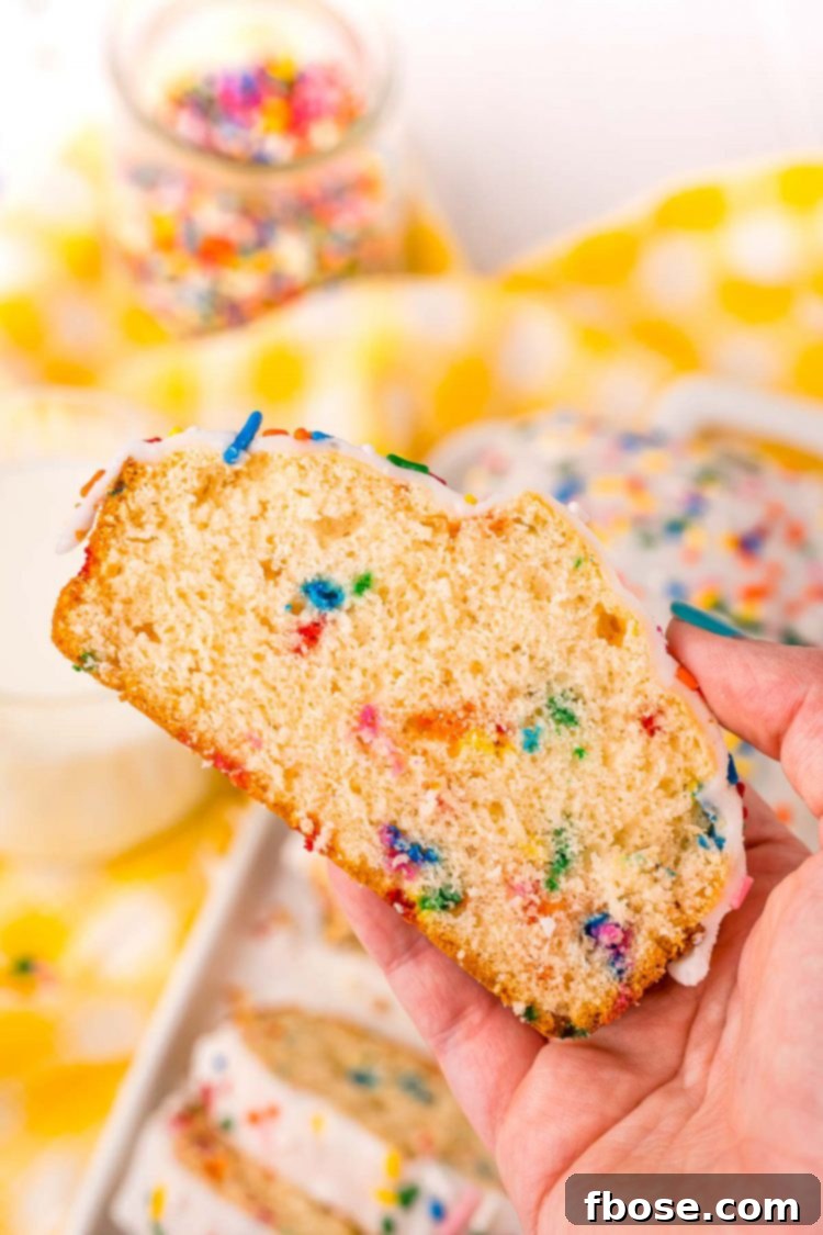 A woman's hand holding a piece of funfetti ice cream bread to the camera.