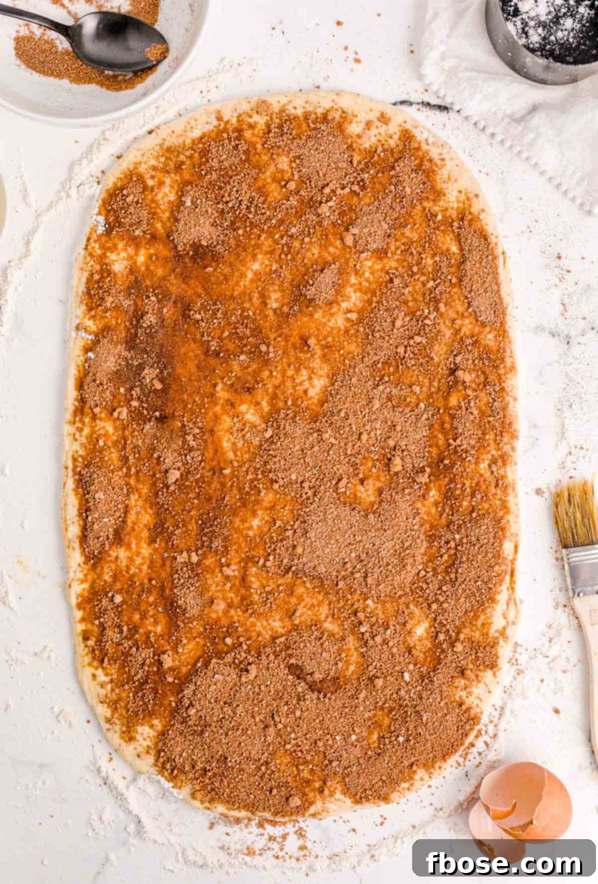 Cinnamon sugar mixture sprinkles on rolled our bread dough.