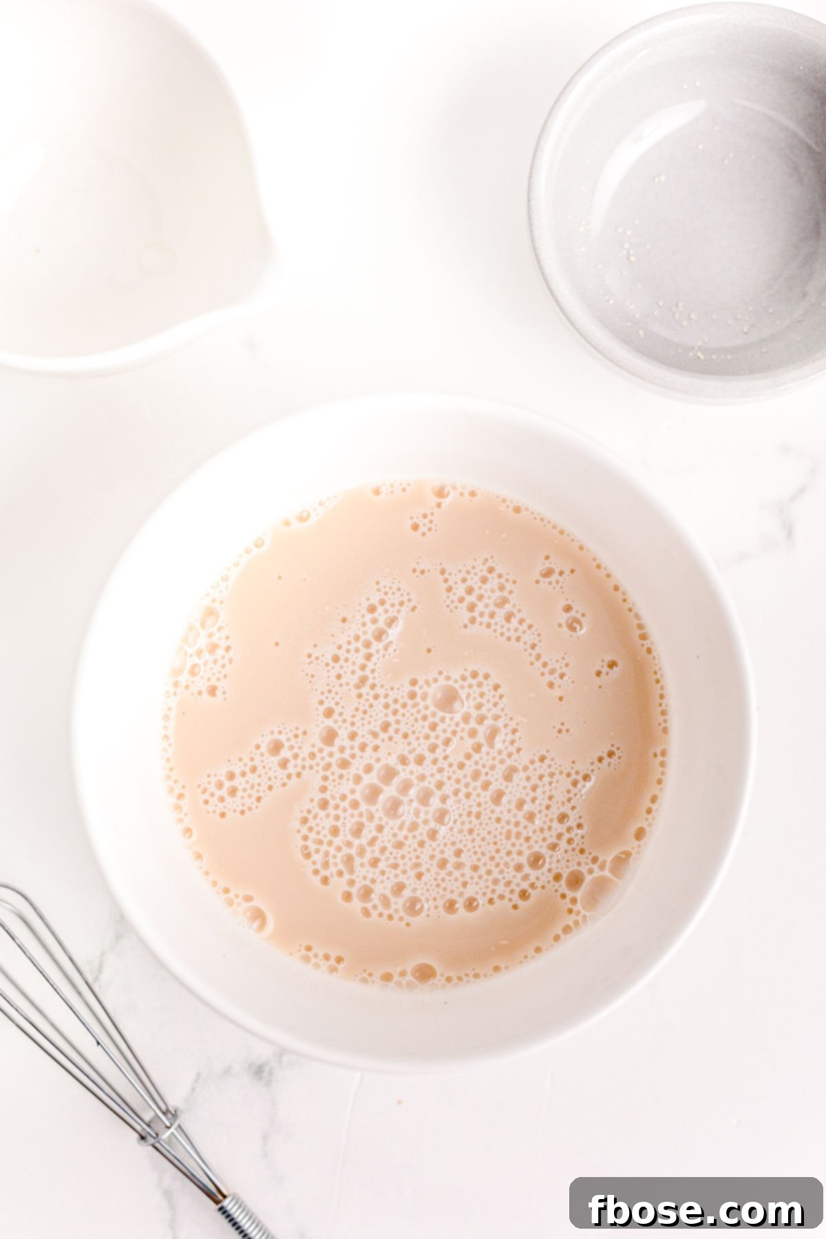 Overhead photo of yeast and water blooming in a white bowl.
