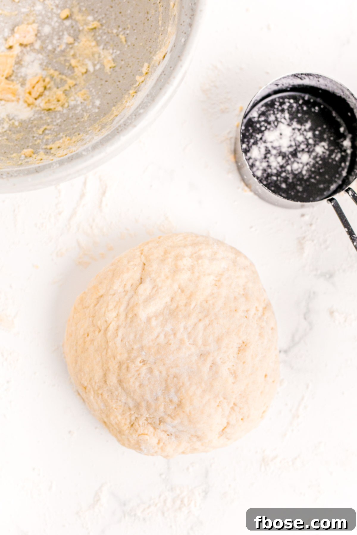 Bread dough in a ball on a floured marble surface.