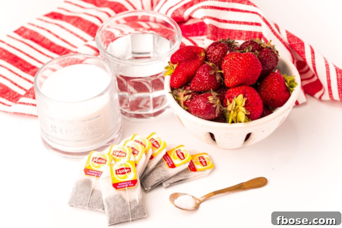 Ingredients used to make strawberry sweet tea laid out on a white table with a white and red striped napkin, including fresh strawberries, tea bags, sugar, and baking soda.