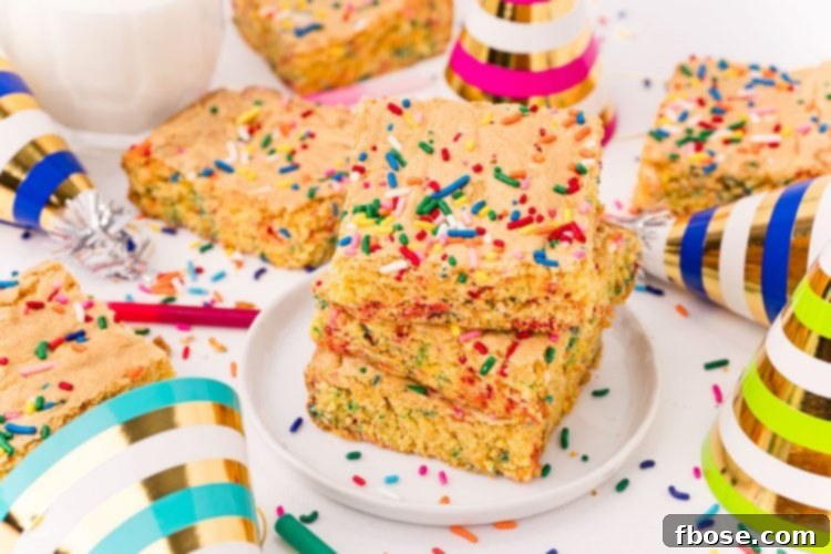 Close up photo of cake mix brownies on a white plate on a white table surrounded by sprinkles and birthday hats.
