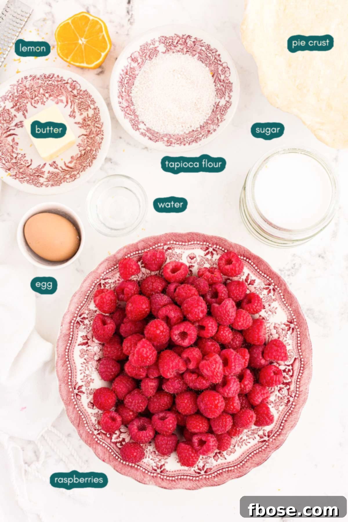 Prepared ingredients for raspberry pie arranged neatly on a white kitchen counter, ready for assembly.
