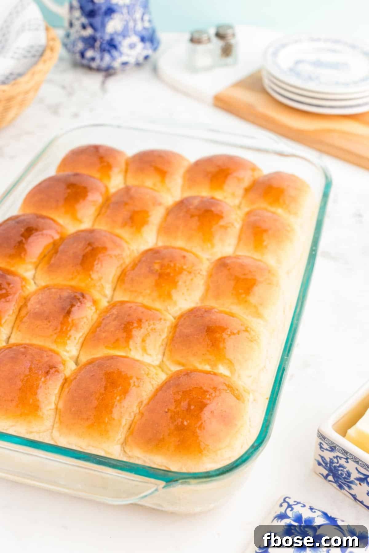 A perfectly baked batch of soft sourdough dinner rolls cooling in a clear glass baking pan, showcasing their golden-brown tops.