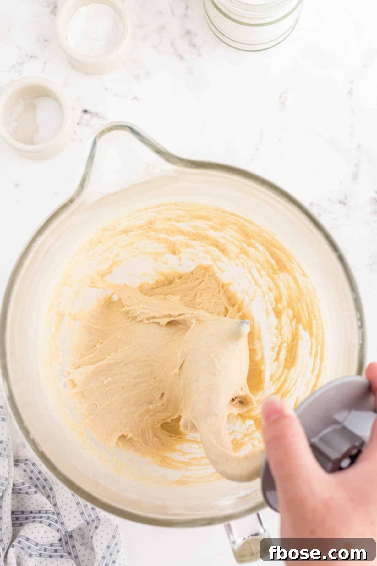 A smooth, elastic dough ball forming around a dough hook in a stand mixer, indicating proper kneading.