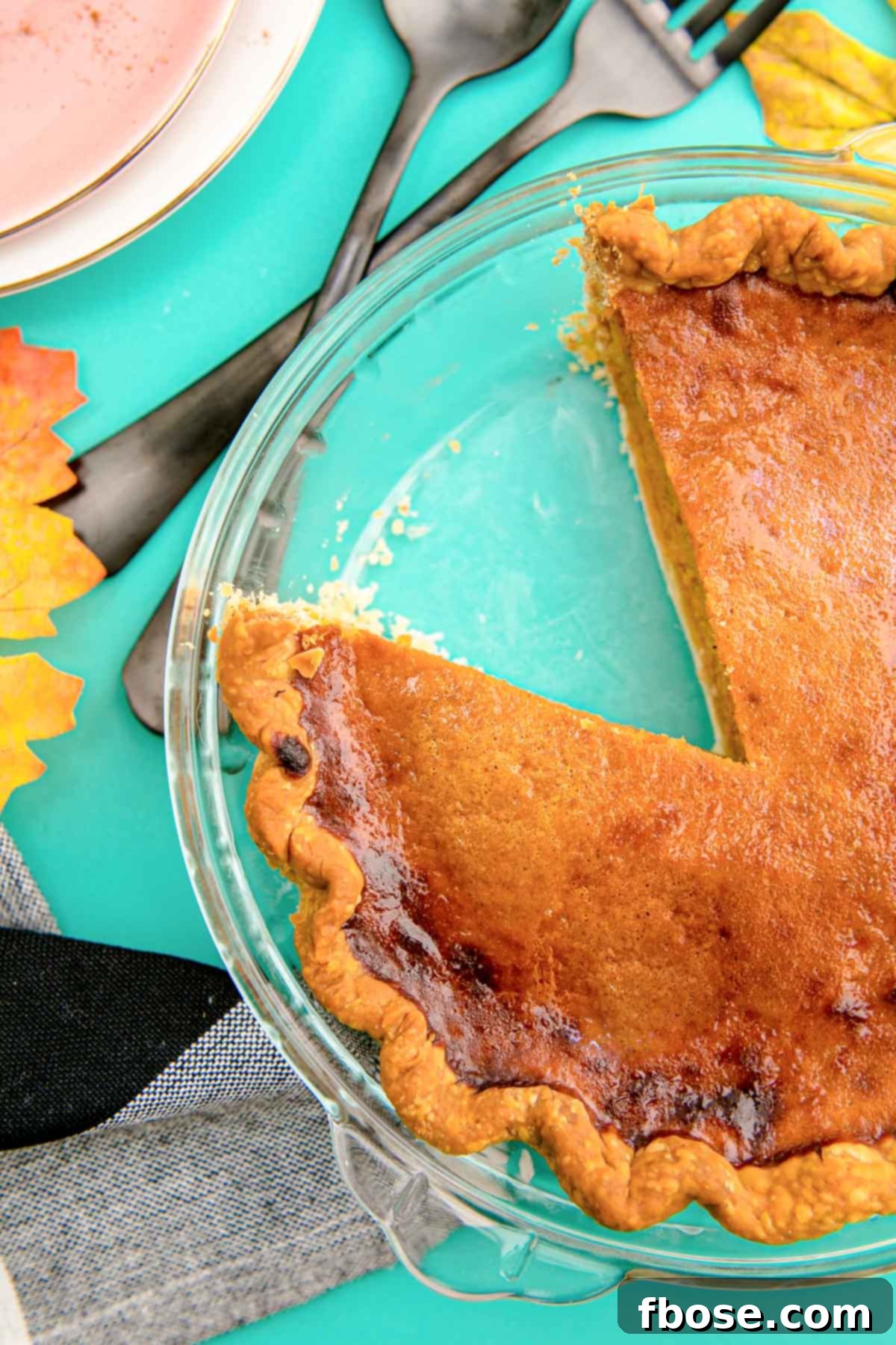 Overhead photo of a pumpkin pie in a glass baking dish with a slice missing.