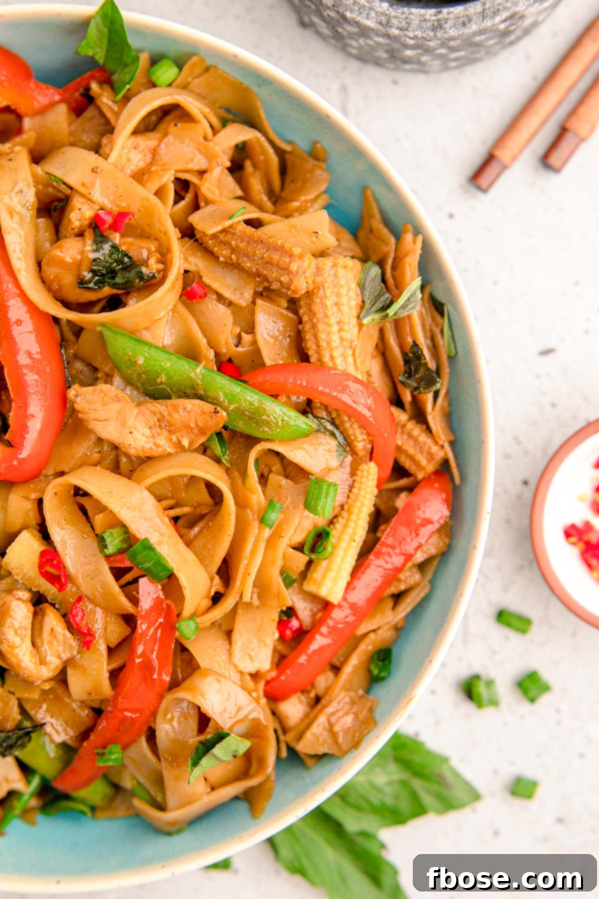 Thai Drunken Noodles in a blue bowl, garnished and ready to enjoy.