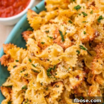Close up photo of Pasta chips in a teal bowl with marinara sauce to the side.