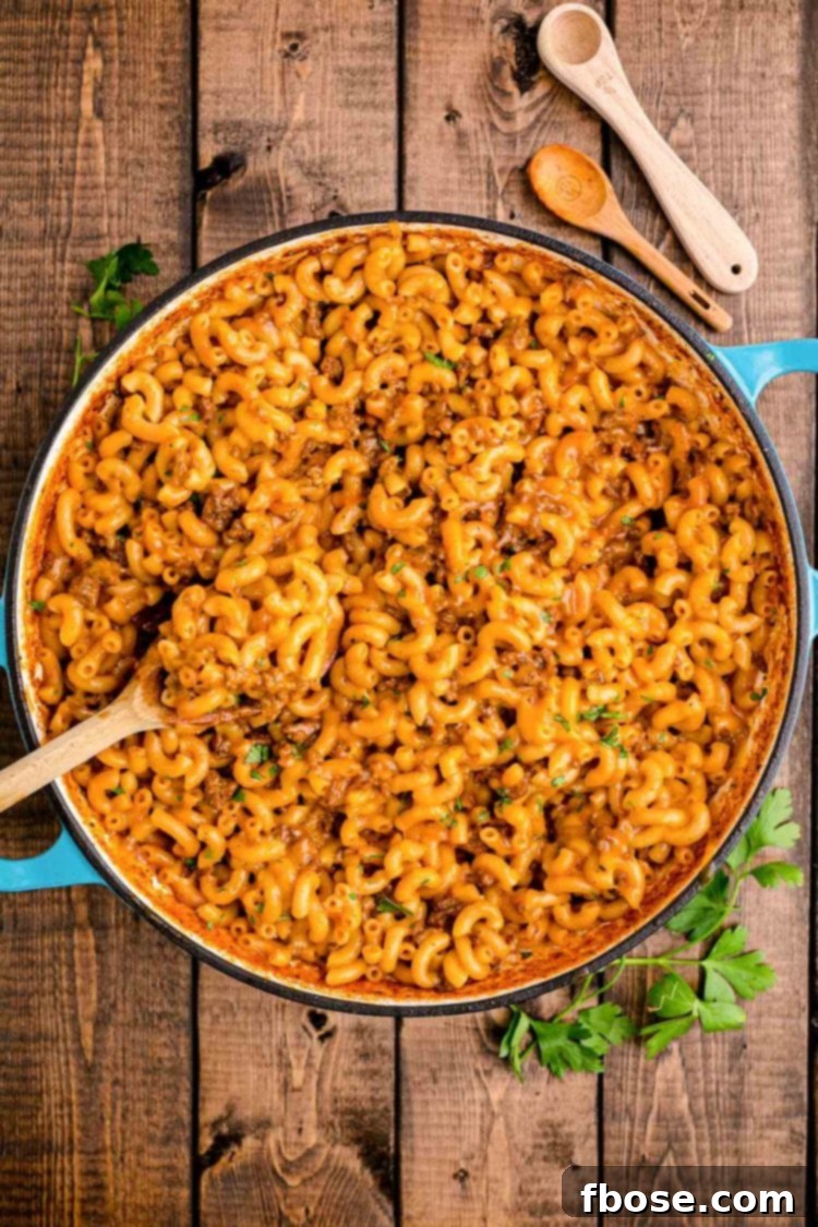 Overhead photo of homemade hamburger helper in a Dutch oven on a wooden table, highlighting its creamy, cheesy texture.