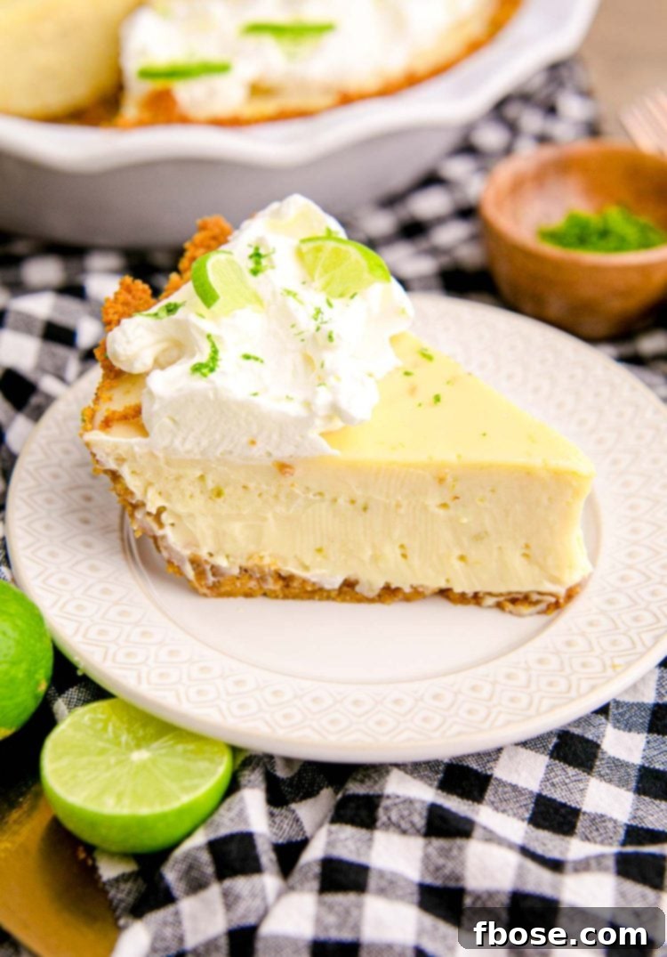 Close up photo of a slice of key lime pie on a white plate on a black and white checkered napkin.