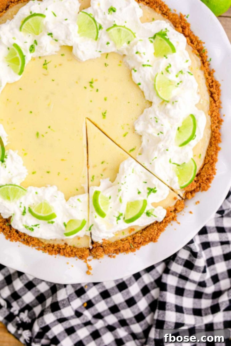 Close up overhead photo of a key lime pie in a white pie dish on a black and white gingham napkin.