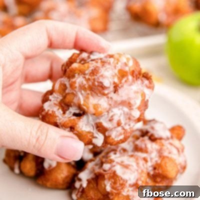 Close up photo of a woman's hand holding an apple fritter.