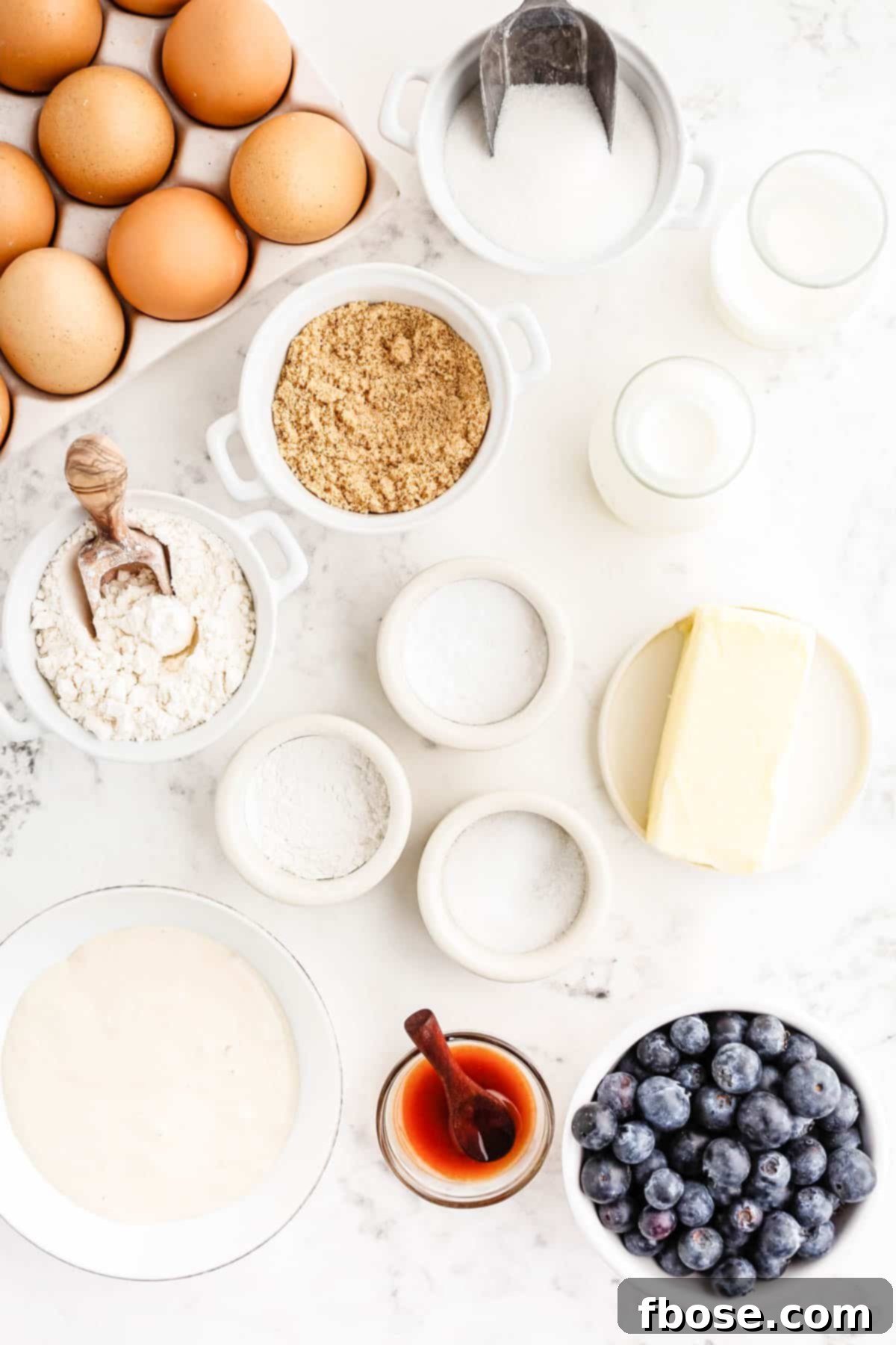 Ingredients to make sourdough blueberry muffins on a white counter.