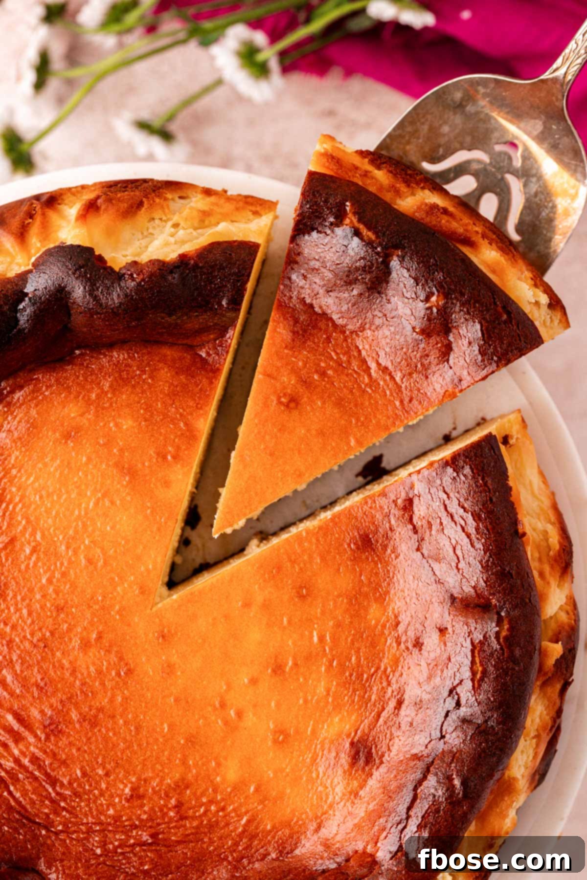 Overhead photo of a basque cheesecake with a slice being removed.