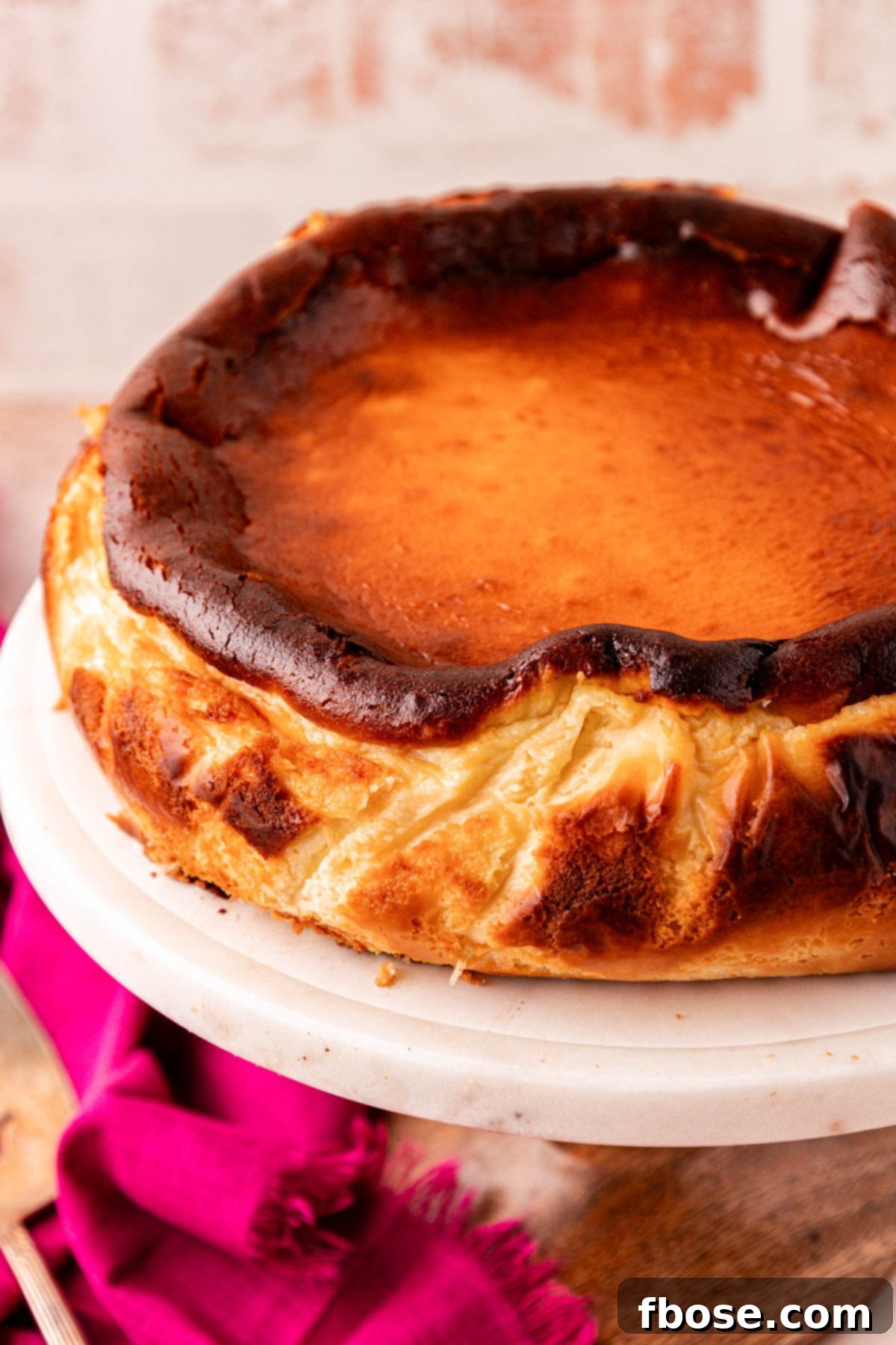 Close up of a whole basque cheesecake on a cake stand.