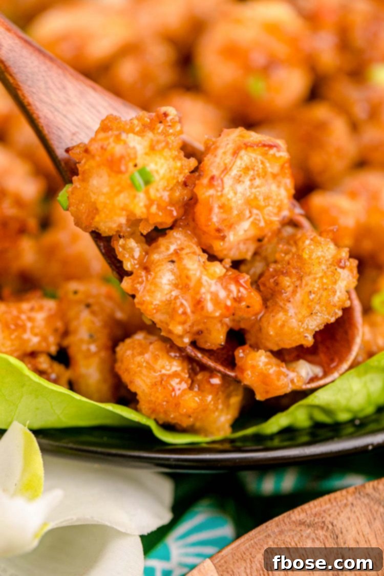 Bang Bang shrimp being scooped off a plate with a wooden spoon.